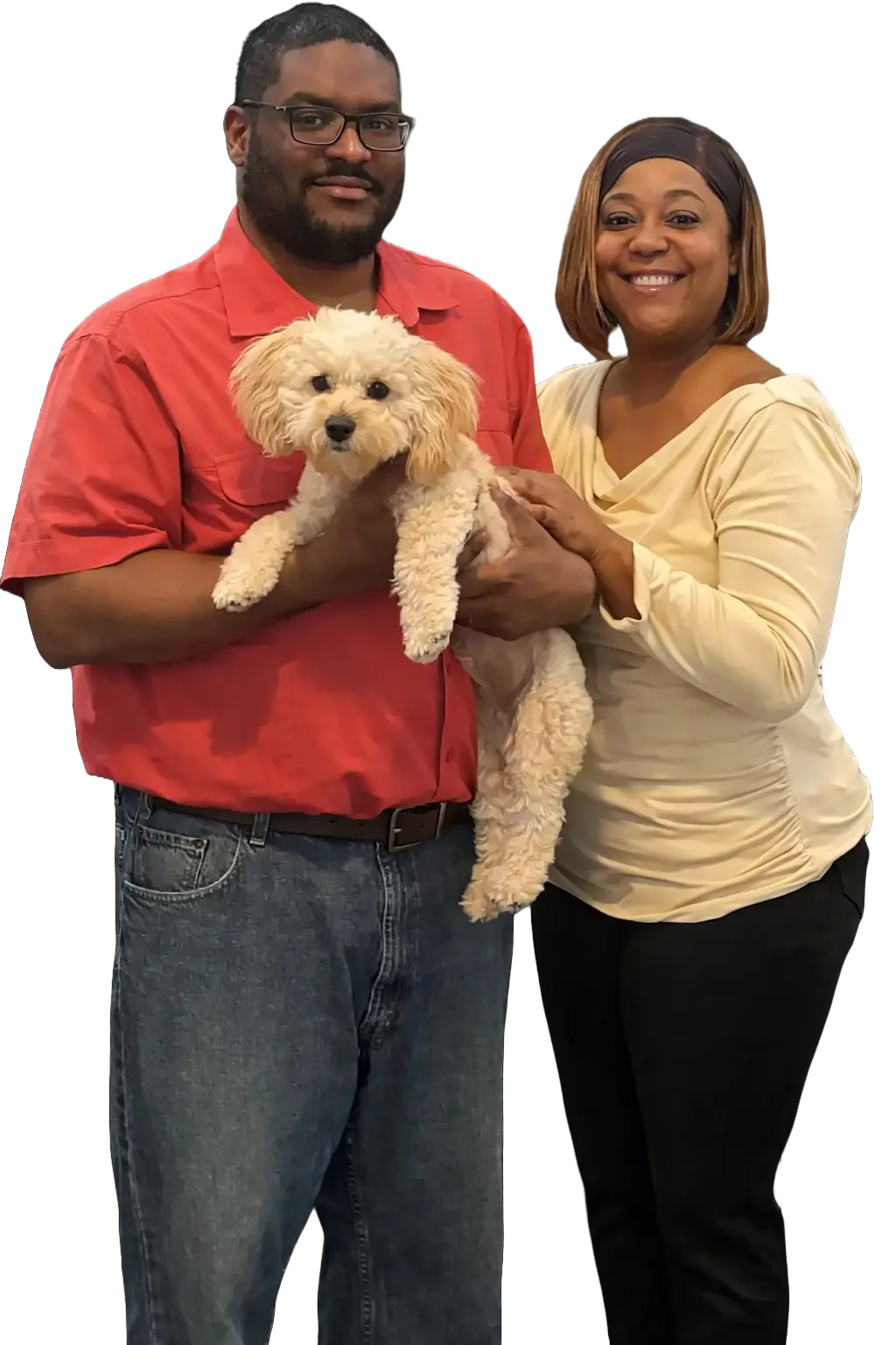 A man in a red shirt and a woman in a beige top posing together while holding a small white puppy.